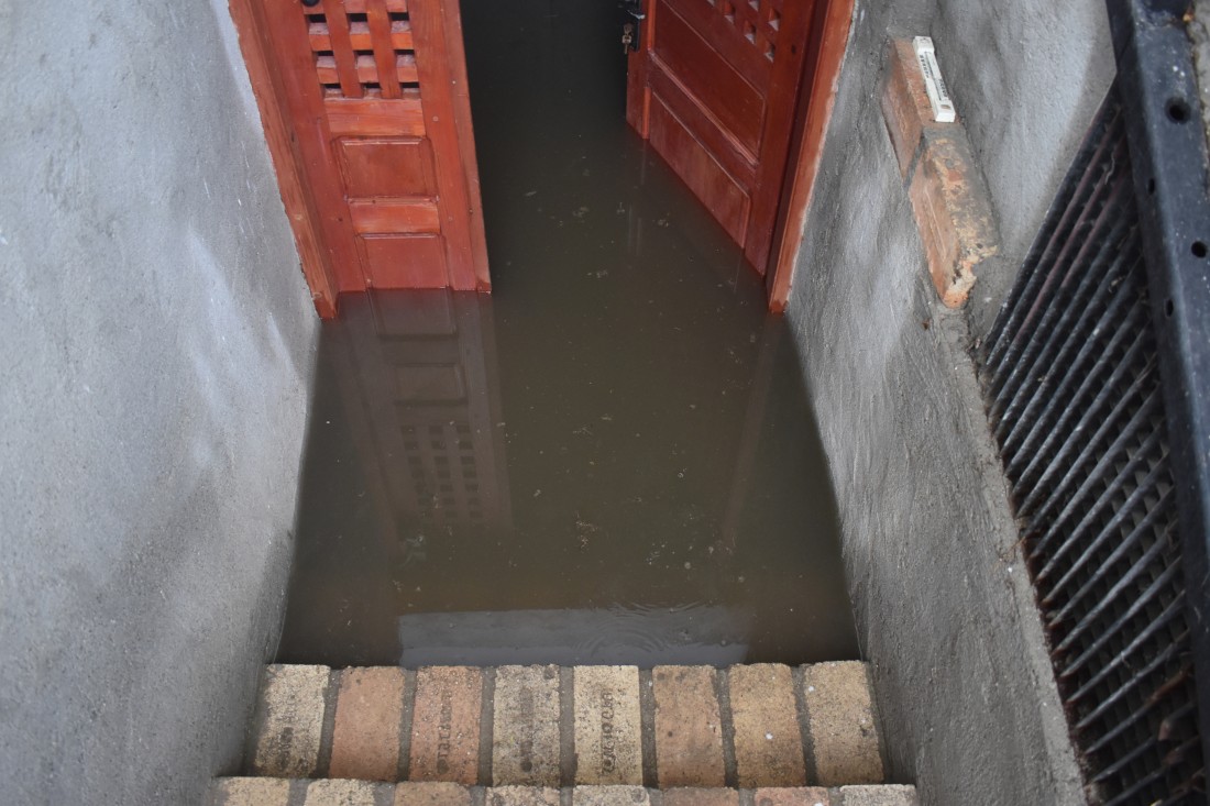 staircase down to a flooded room with doors. The right door is open.